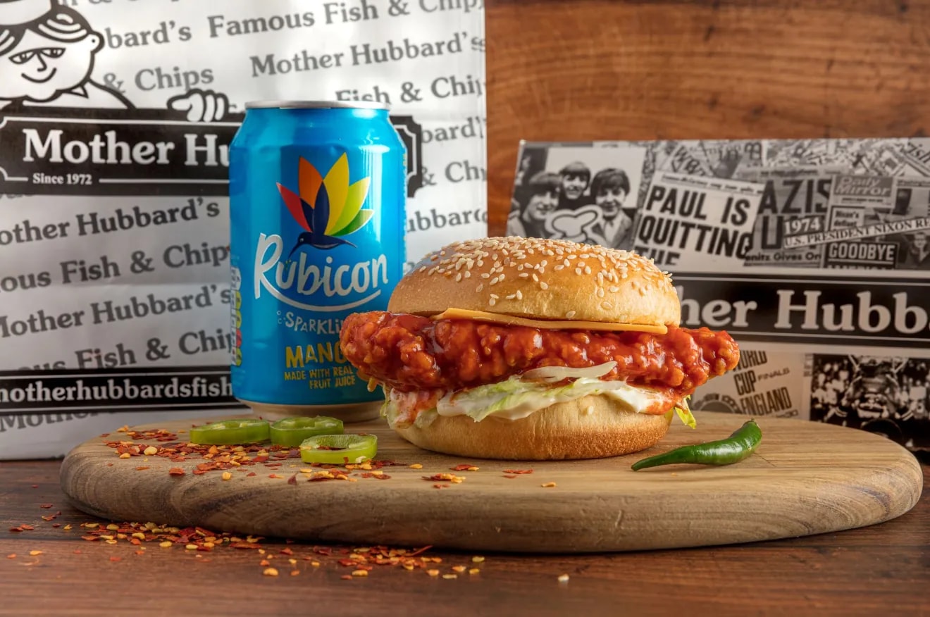 A dynamite chicken sandwich in a sesame bun with chillies, beside a can of Rubicon
