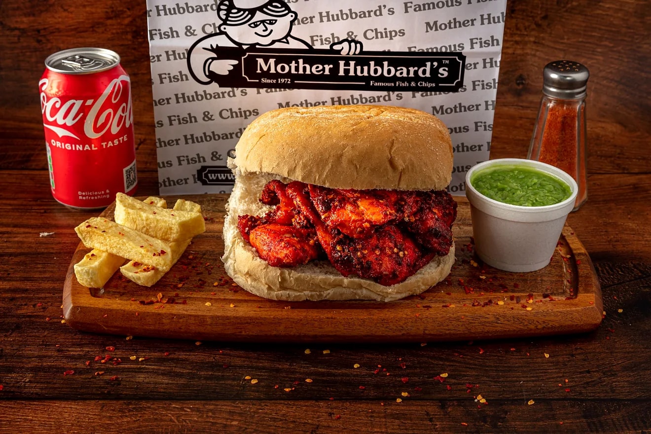 A fiery fish butty in a bread roll with chips and sauces