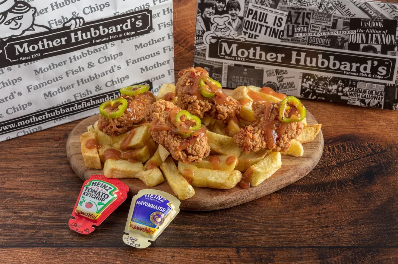 Hot wings with sauce and jalapeño slices on chips, with ketchup and mayonnaise sachets