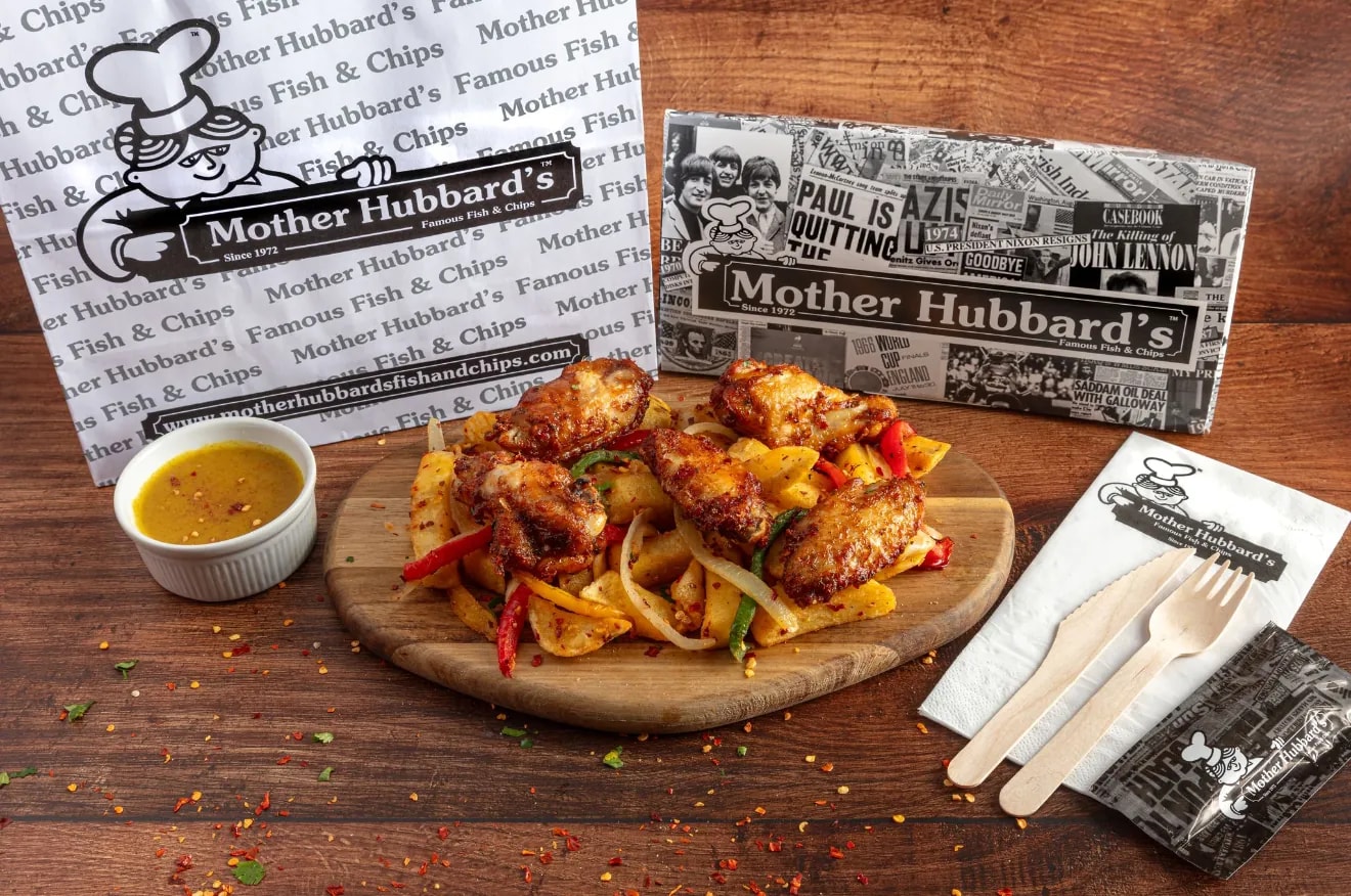 Salt and pepper wings with peppers and onions on a board, with curry sauce and wooden cutlery