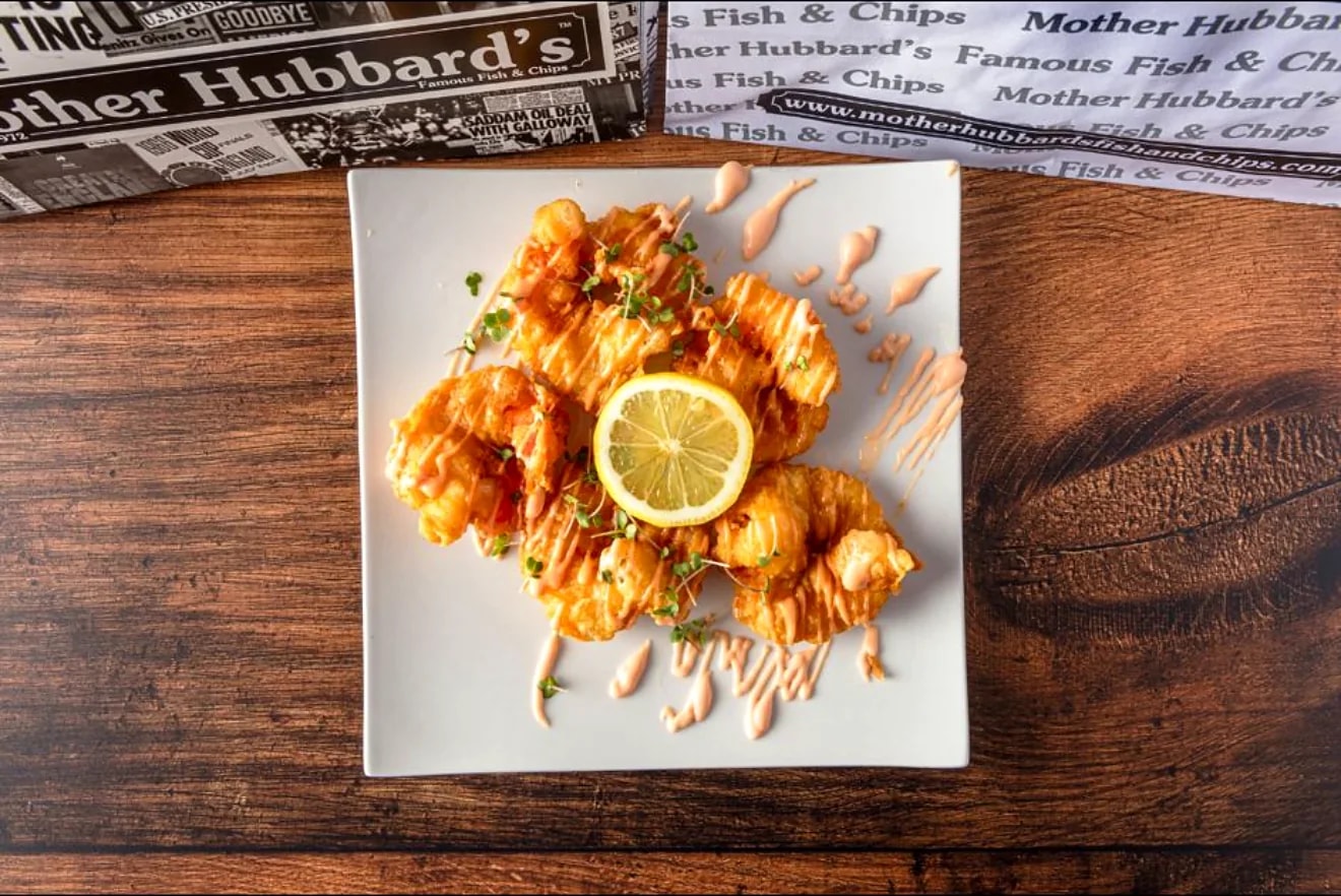 Battered prawns arranged on a white plate with lemon