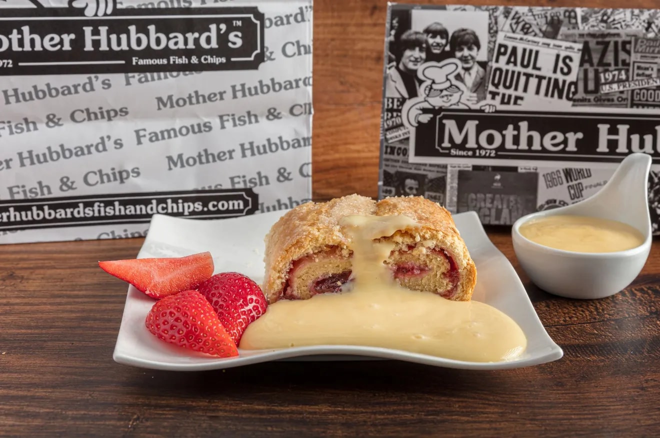 Jam roly poly with custard and strawberries, with a pot of custard