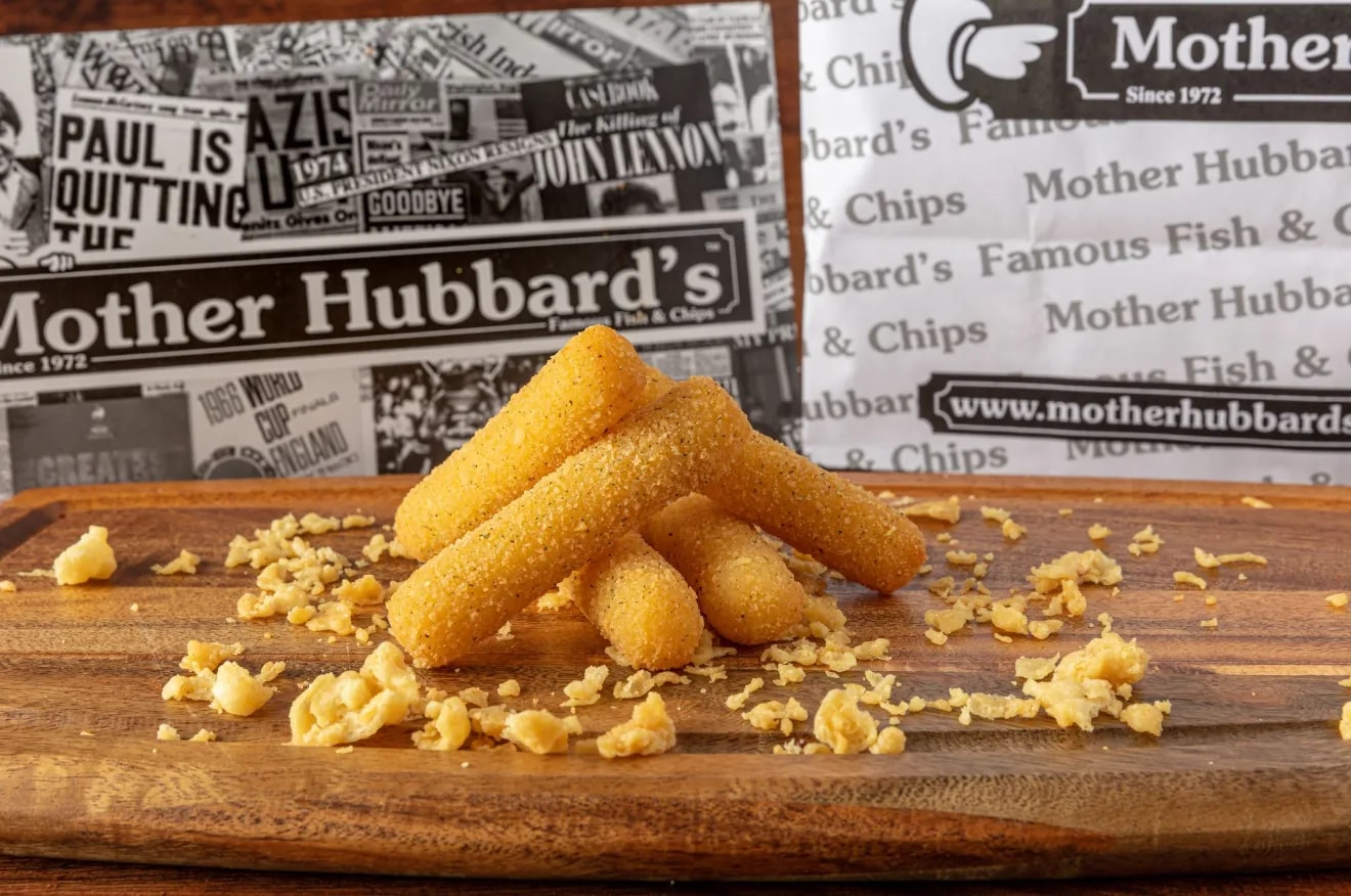 Breaded mozzarella dippers stacked on a wooden board