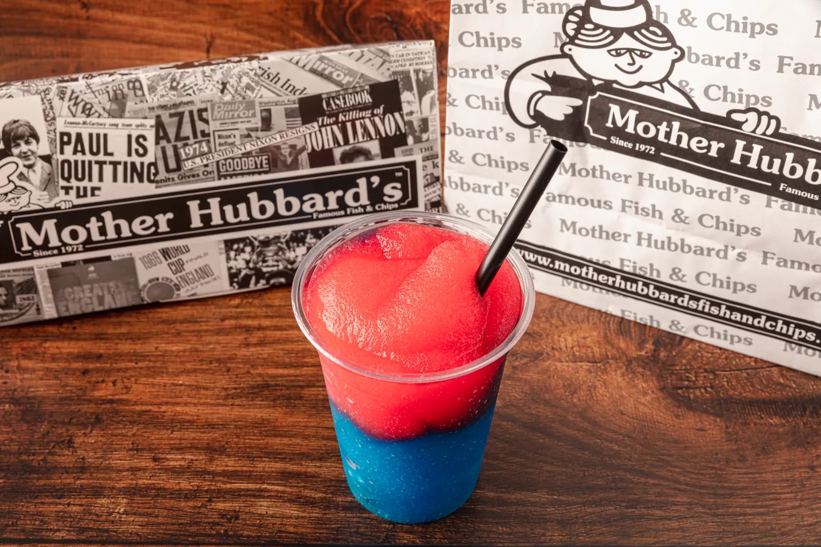 A red and blue layered slush with a black straw, in front of Mother Hubbard’s paper